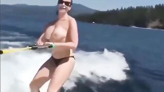 Topless girl water skiing on the tube
