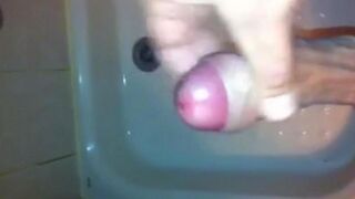 The kid caresses his dick with his hand while standing in the shower stream