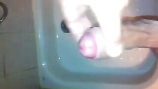 The kid caresses his dick with his hand while standing in the shower stream