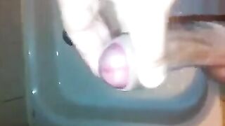 The kid caresses his dick with his hand while standing in the shower stream