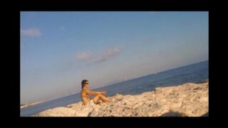A completely naked girl is basking in the sun at the beach