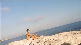 A completely naked girl is basking in the sun at the beach