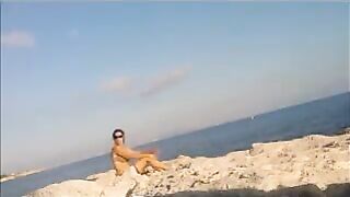 A completely naked girl is basking in the sun at the beach