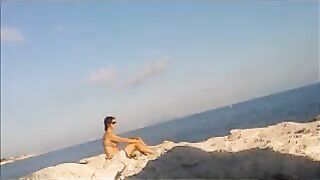 A completely naked girl is basking in the sun at the beach
