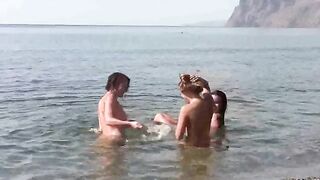 A group of people without clothes rest on the beach and play with each other