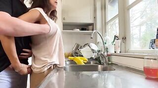 A woman with big natural tits is being fucked from behind in the kitchen