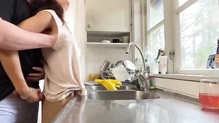 A woman with big natural tits is being fucked from behind in the kitchen