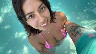 A girl in a bikini is having fun by the pool with someone